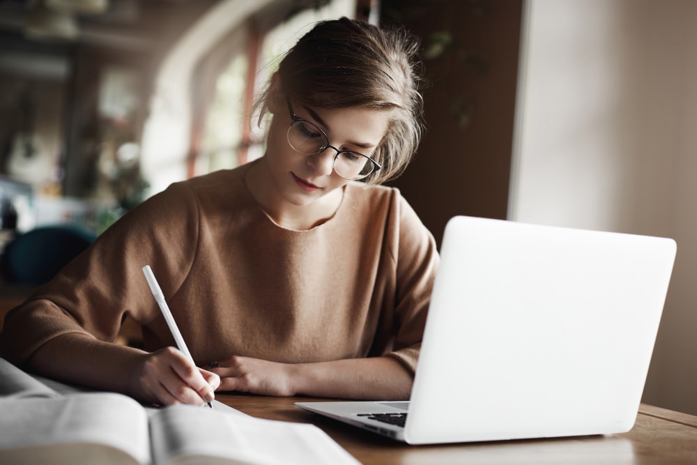 Studentin macht sich konzentriert Notizen am Laptop