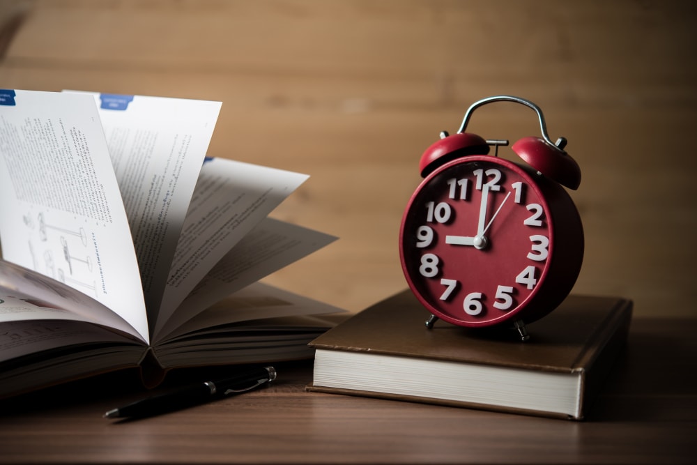 Wecker neben einem aufgeschlagenen Buch